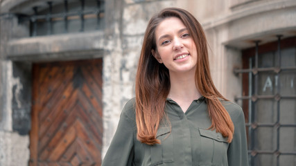 Close up portrait of a beautiful smiling girl with brown hair. Urban city background