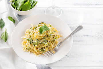 pasta with spinach and cheese on a plate , fork, fresh spinach leaves on a light background ,  copy space