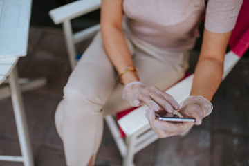 Attractive young caucasian woman with mask, gloves and phone in cafe