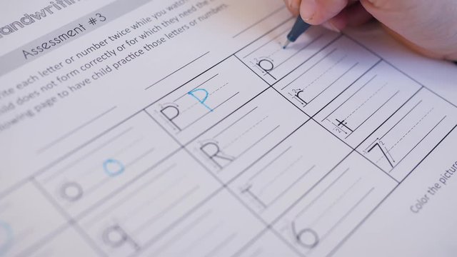 Close-up Shot of A Child Writing Alphabets. Hand held action video as kid is learning to write English characters.