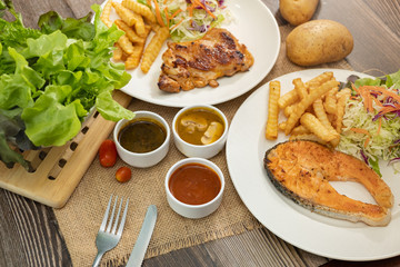 Salmon fish and Chicken grilled steak dishes with barbecue, mushroom and black pepper sauce. Wooden table.