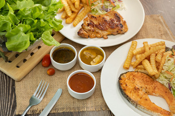 Salmon fish and Chicken grilled steak dishes with barbecue, mushroom and black pepper sauce. Wooden table.