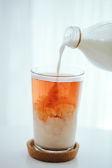 pouring milk into a black tea glass