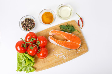 salmon steak with vegetables and spices on a white background. The concept of cooking. Grocery background.Salmon steak, raw fish cooked for cooking. Top view	