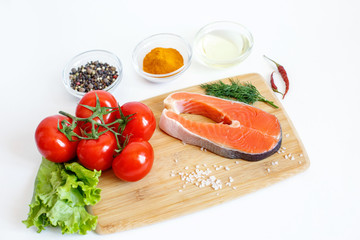 salmon steak with vegetables and spices on a white background. The concept of cooking. Grocery background.Salmon steak, raw fish cooked for cooking. Top view	