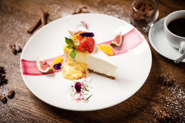 Cheesecake with passionfruit fig and orange sauce on a white plate. Delicious healthy gourmet dessert food closup served for dinner in restaurant.