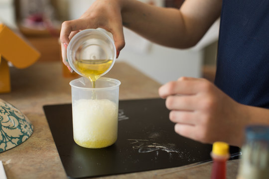Close up of young student learning at home pouring chemicals in beakers with experiment lab