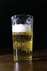 Glass of light beer on a dark background.