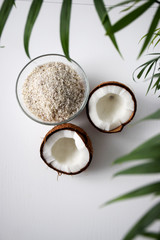 Fototapeta na wymiar Cracked coconut in leaves of palm tree on white