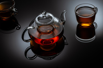 glass teapot and cups with hot tea on table, close view  
