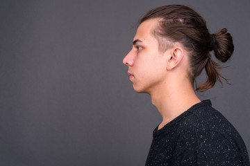 Closeup profile view of young handsome man with hair tied