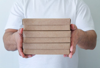 Male hands holding cardboard containers on white background. Takeaway food concept. Food delivery service. Postman giving eco carton boxes