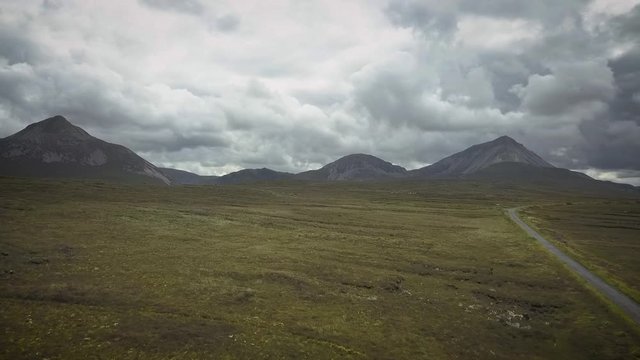 Aerial of mountain landscape under moody clouds.  Reveals a lake.
