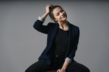 Portrait of a beautiful young business woman standing against grey wall