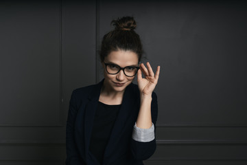 Portrait of a beautiful young business woman standing against black wall