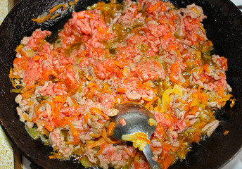 Half-cooked minced meat is fried in a pan with carrots.