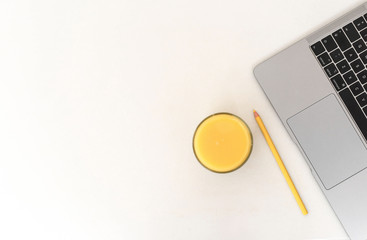 Laptop and orange juice on white table