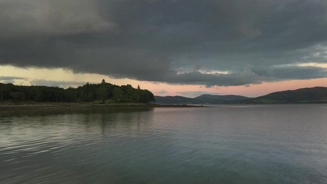Aerial rise over still lake with orange sunset.