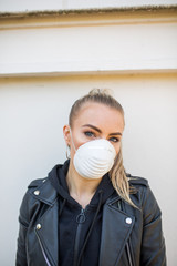 Junge Frau mit Lederjacke trägt Maske Sprayer, Corona, Schutz, Selbstschutzmaske, Vermummung, Blond