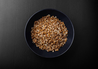 blue plate with buckwheat porridge on the black table
