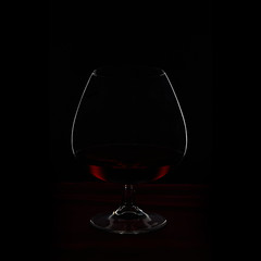 outline of a cognac glass on a dark background