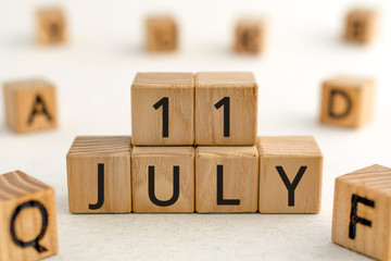 July 11 - from wooden blocks with letters, important date concept, white background random letters around