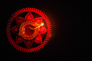 top view of beautiful clay diya and rangoli art on black background with copy space. festival of lights