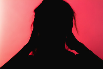 silhouette of worried girl clutched hands behind head in panic, unrecognizable woman on red background, concept life problems, stress,destructive emotions
