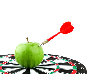 concept of successful work. dart sticks out of an apple on a dart board. dart hit an apple on a...