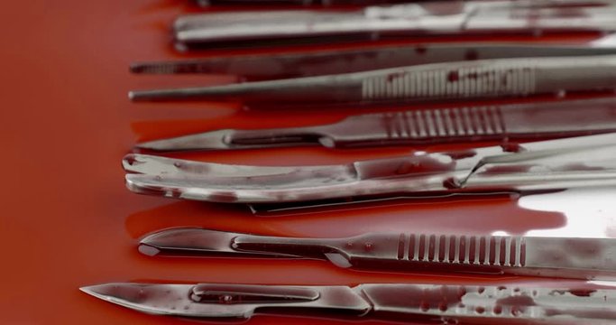 Truck shot close up of surgical instrument tools with blood, scalpel forceps tweezers, scissors for surgeon in surgery