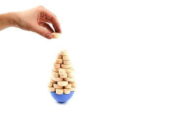 Obraz premium Risk management concept on white background. hand holds an additional load over the unstable structure. wooden balance game on white background