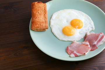 two fried eggs is on the plate on dark wooden background