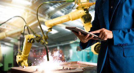 Manager or Industrial engineer working and control robotic with industry factory and network connection automation robot arm by tablet. AI, Artificial intelligence.