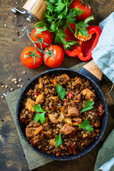 Indian cuisine dish. Traditional indian spicy green lentils with meat, spices, herbs in a cast-iron frying pan on a wooden table. Top view flat lay background. Copy space.