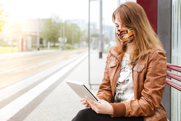 Frau wartet an Haltestelle mit Reader