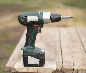 Cordless screwdriver stands on a wooden table