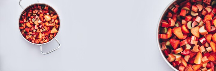 Rhubarb and strawberry in a cooking pan cut in pieces to prepare jam at home. Long banner.