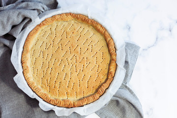 close-up traditional homemade pie Crostata, shortcrust pastry base,  on the marble table before being filled.Top view.
