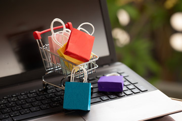 Paper shopping bags in a trolley or shopping cart on keyboard. Concept about online shopping that...