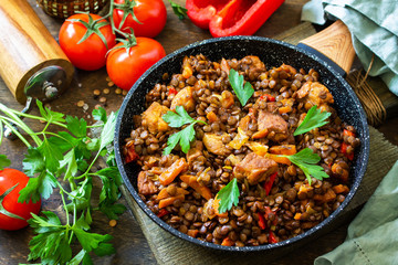Indian cuisine dish. Traditional indian spicy green lentils with meat, spices, herbs in a cast-iron frying pan on a wooden table.