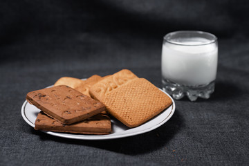 Cookies on a white plate and a glass of milk. Milk products. Photo of food on a dark background.