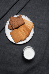 Cookies on a white plate and a glass of milk. Milk products. Photo of food on a dark background.