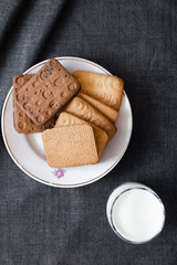 Cookies on a white plate and a glass of milk. Milk products. Photo of food on a dark background.