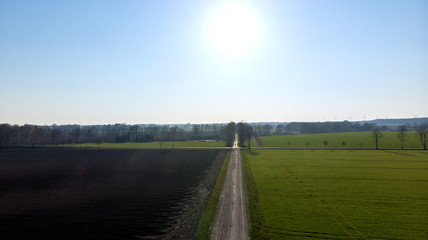 Feldweg zwischen Feldern mit Wiese und Acker im Frühling oder Sommer