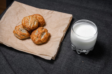Buns from the Kraft oven, food paper and dairy products, a glass of milk.
Photo on a dark background.