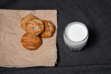 Buns from the Kraft oven, food paper and dairy products, a glass of milk.
Photo on a dark background.