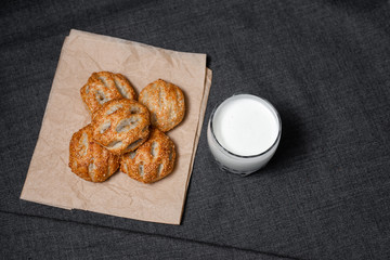 Buns from the Kraft oven, food paper and dairy products, a glass of milk.
Photo on a dark background.