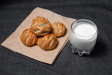 Buns from the Kraft oven, food paper and dairy products, a glass of milk.
Photo on a dark background.