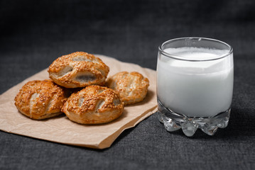 Buns from the Kraft oven, food paper and dairy products, a glass of milk.
Photo on a dark background.