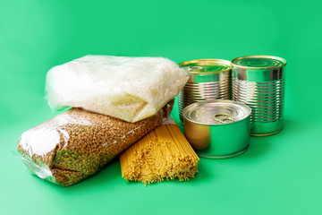 food for donations on a green background. Buckwheat, rice and pasta, canned food for people. Food delivery home.